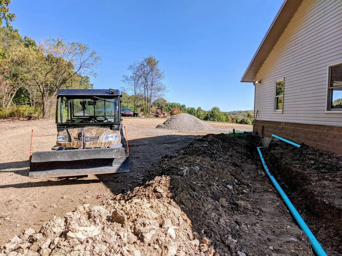 Open trench and drainage pipe beside a building